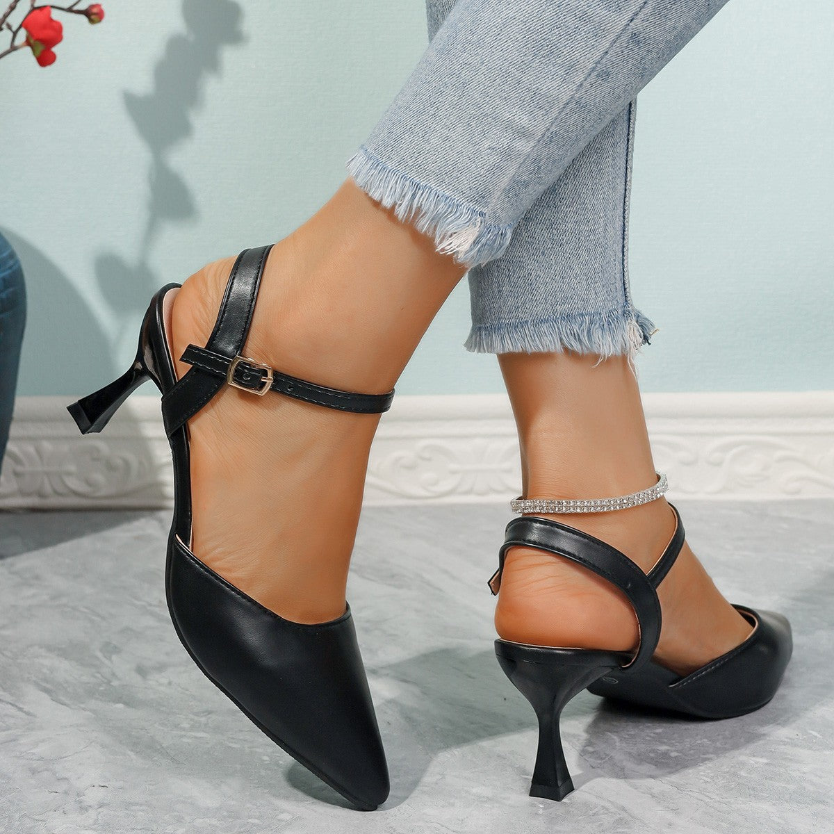 Black pointed-toe slingback heels shown from the back with buckled ankle straps