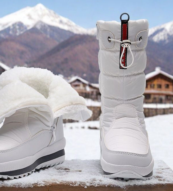 White mid-calf snow boots, quilted puffer style, lace-up with side strap pull.