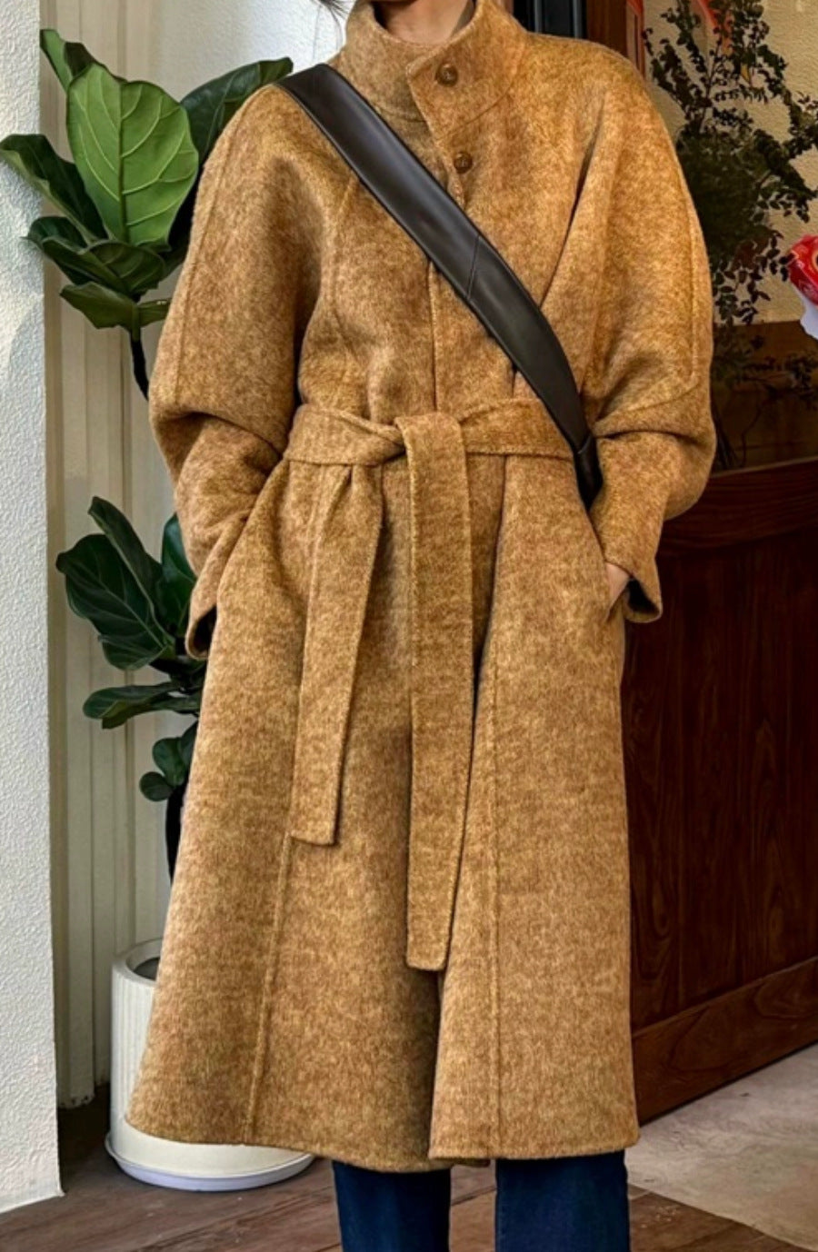 Brown long wool coat with stand collar, button front, tied waist belt, roomy sleeves