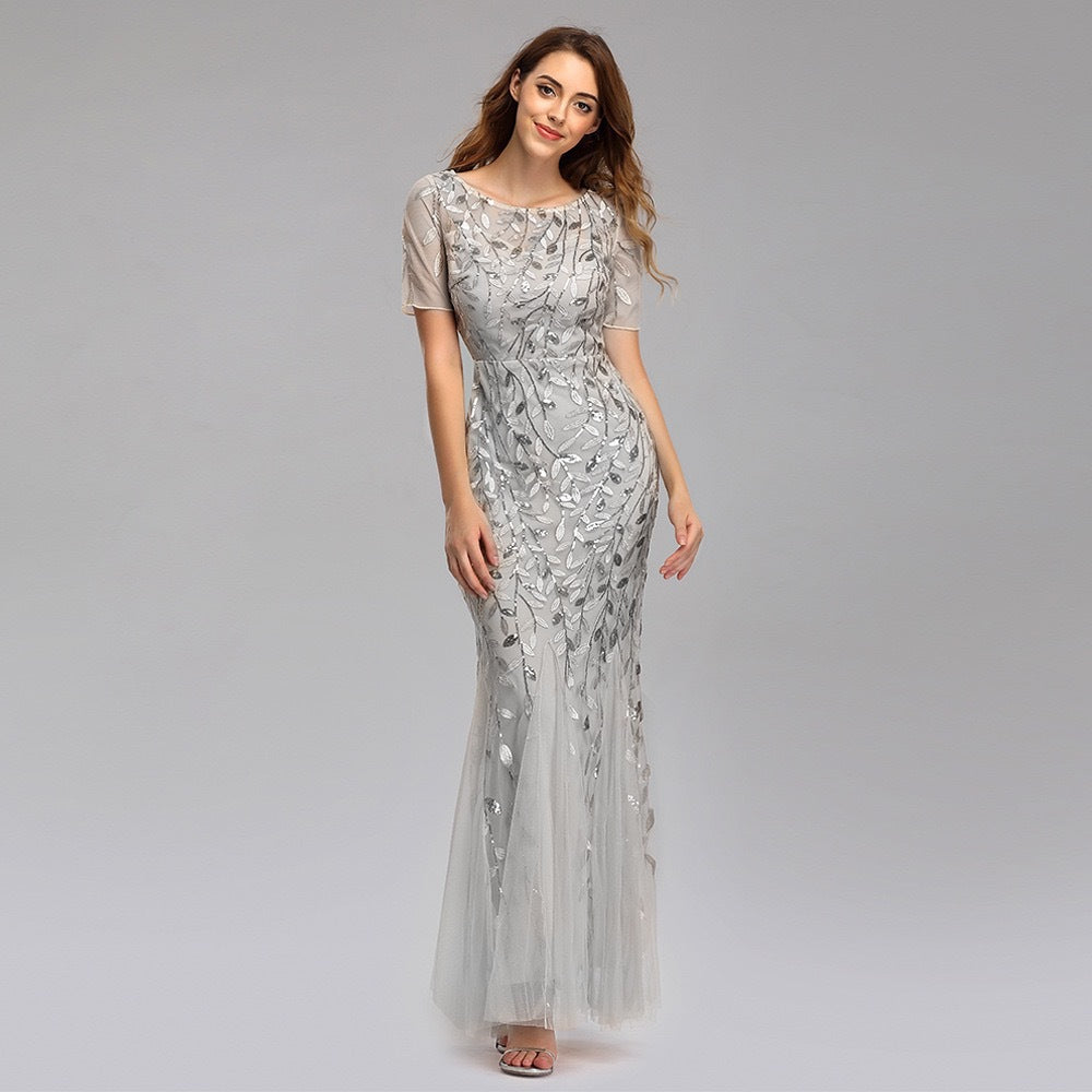 Silver sequin mesh mermaid evening gown with short sleeves and flowing tulle hem.