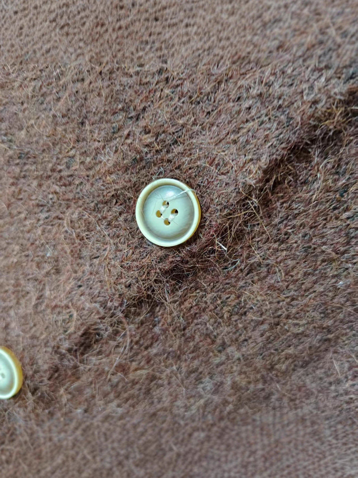 Close-up of brown knit cardigan fabric with light buttons