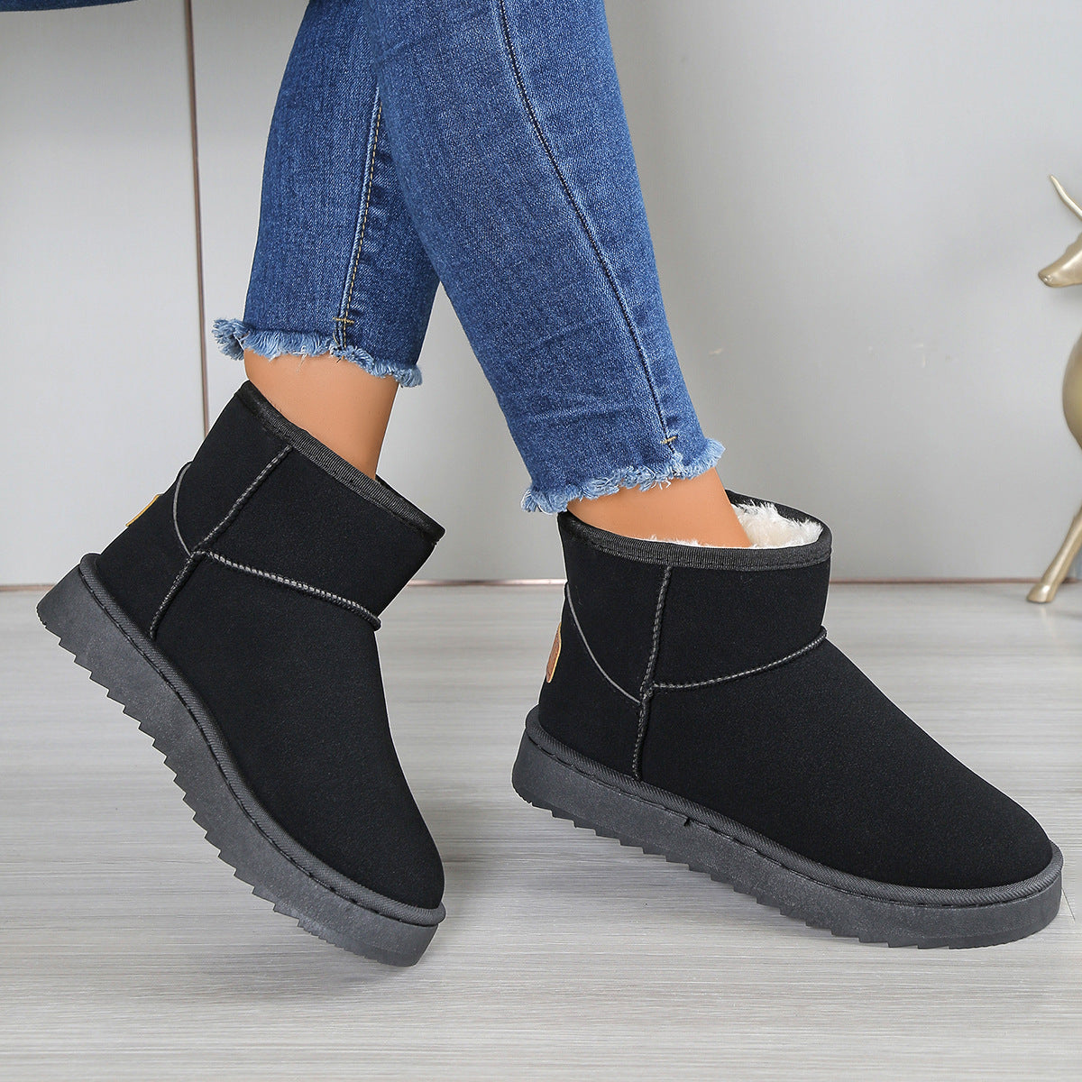 Fleece-lined snow boots in black suede with thick outsole, ankle seam, and white lining