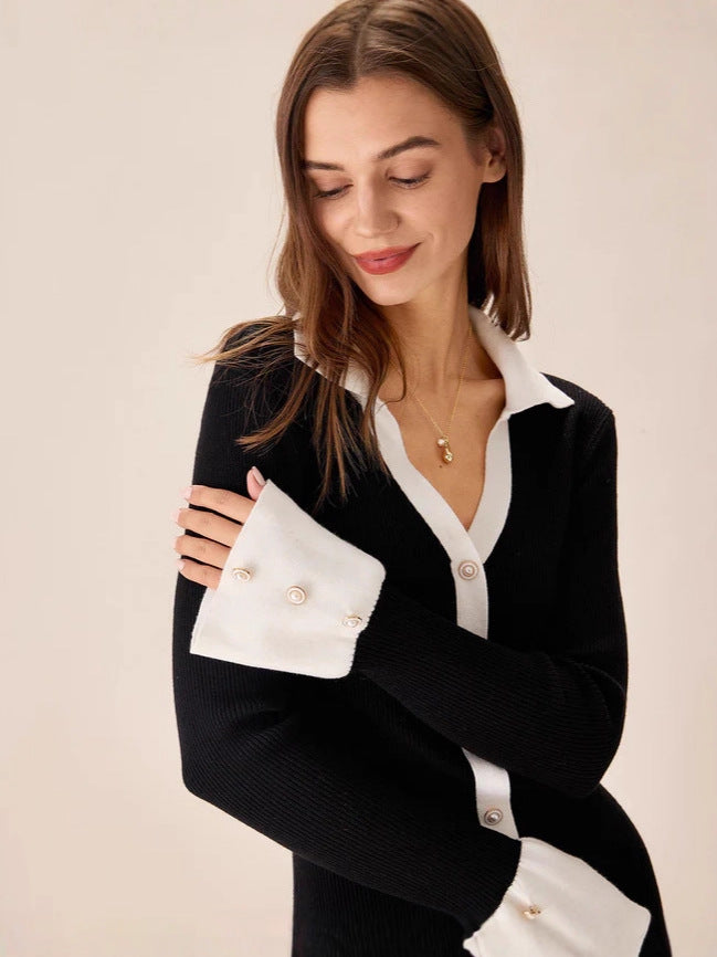 Black knit mini dress detail with V collar, white trim, front buttons, and ruffle hem