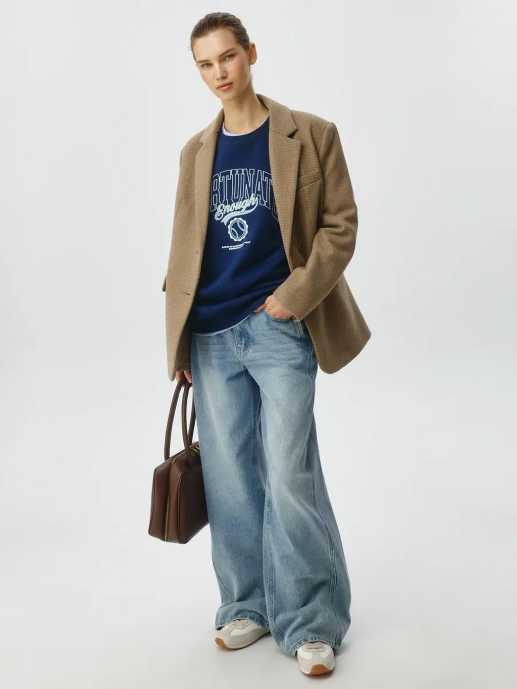 Dark blue crewneck sweatshirt under a tan jacket, long sleeves