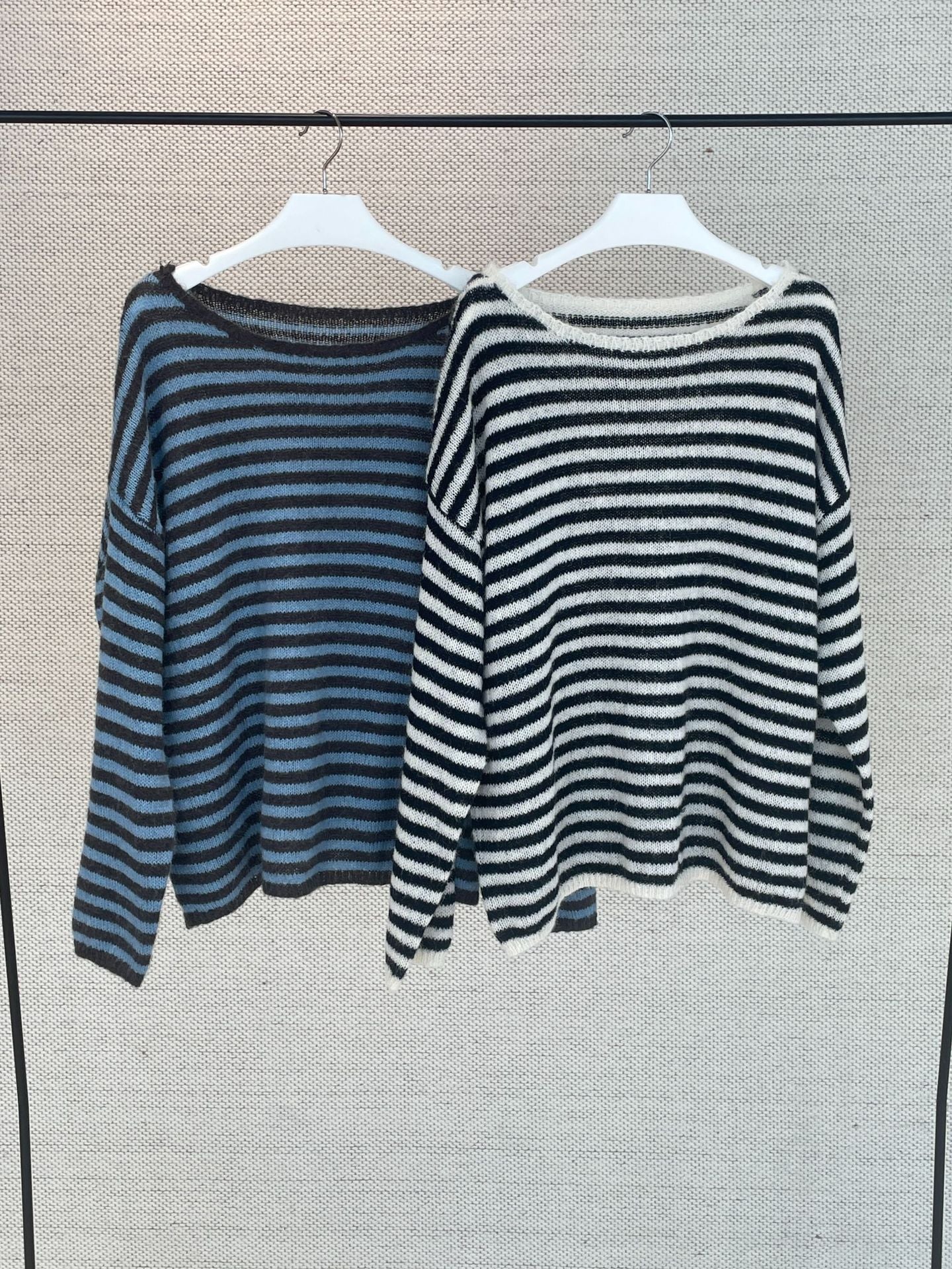 Striped wool sweaters on hangers: blue-and-gray and black-and-white, round neck.