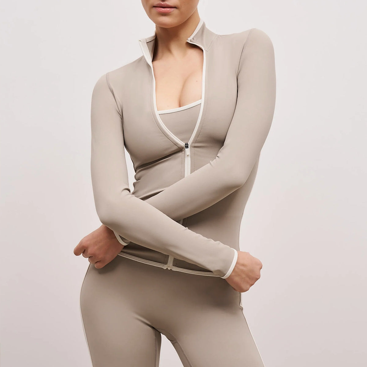 Light taupe yoga jacket with white piping and partly open zipper