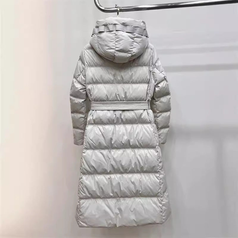 Silver long puffer coat with belted waist, hooded neckline, shiny horizontal quilted finish
