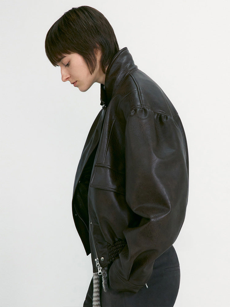 Women's black leather jacket side view with snap-cuff zippers and zip pocket