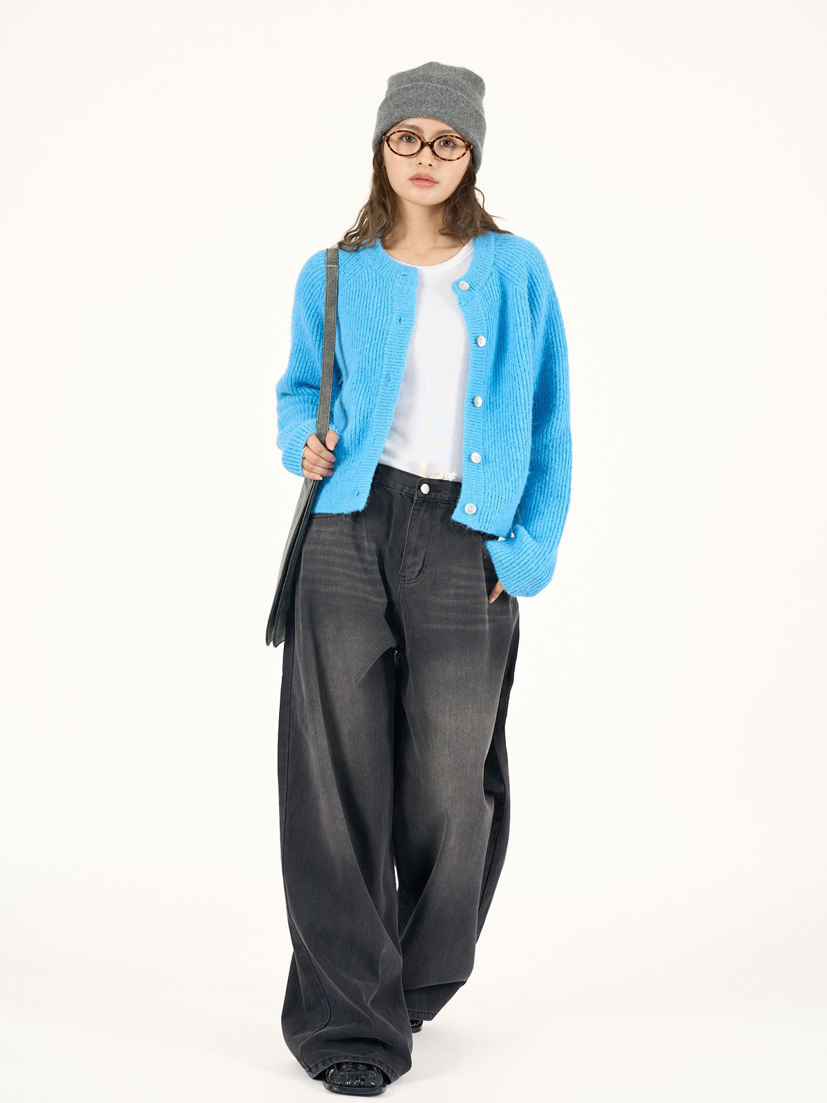 Blue button-front knitted cardigan worn open over a white top