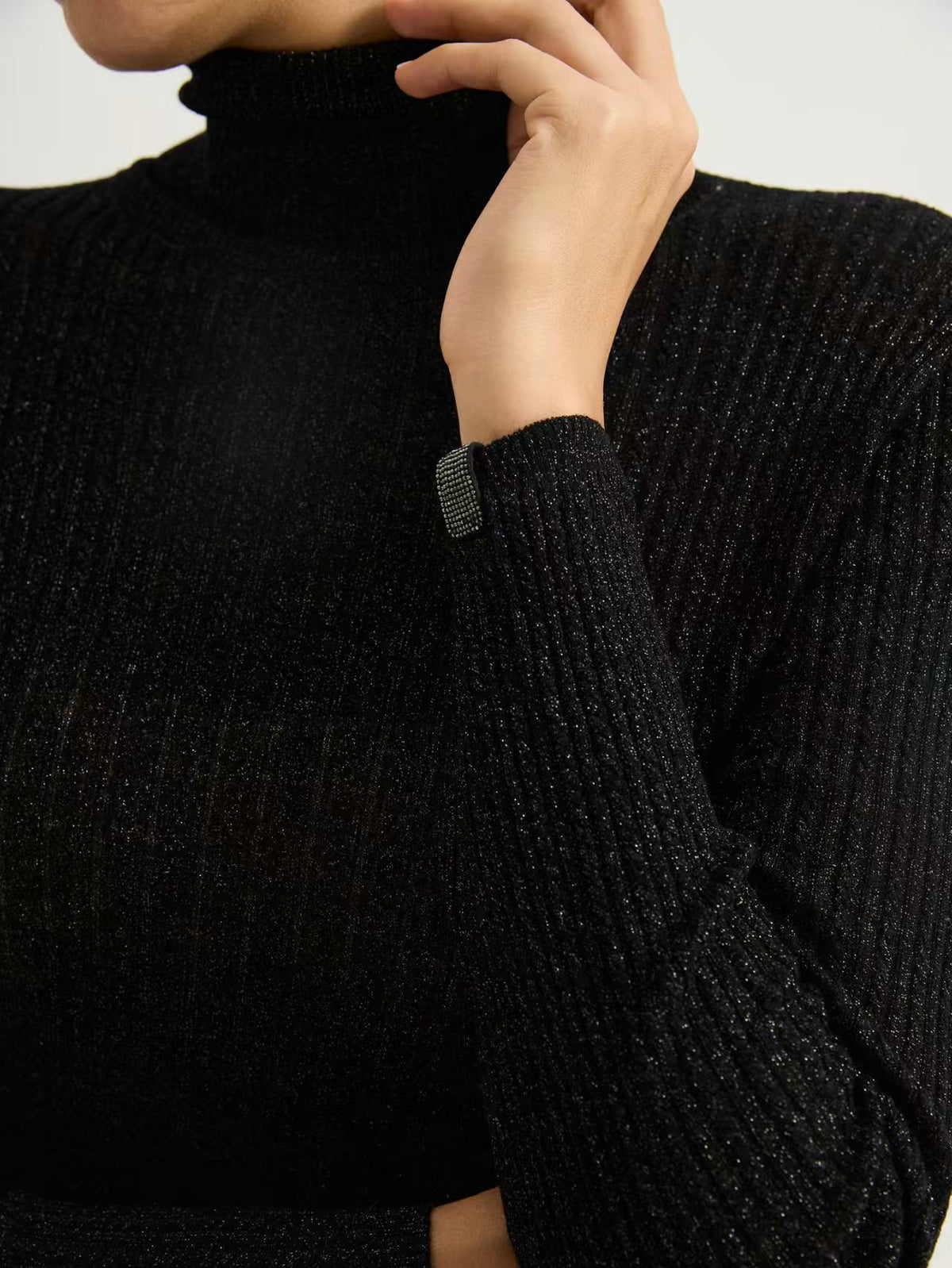 Black high-neck knit sweater sleeve cuff and textured rib detail