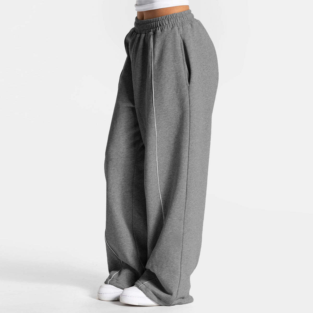 Loose yoga pants in dark gray with elastic waistband and vertical side stripe.