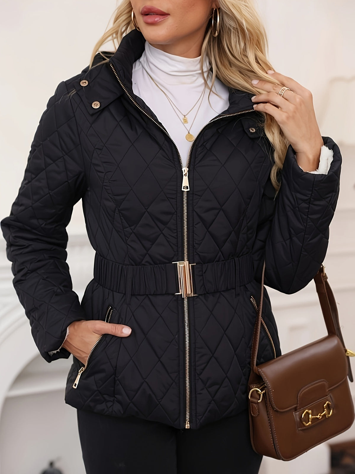 Black quilted zip-up jacket with elastic waist and gold-tone hardware, hood