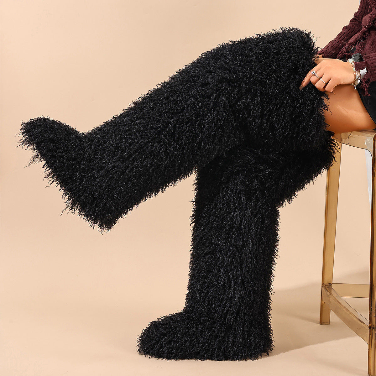 Black faux-fur thigh-high boots with long pile, shown worn with one leg raised.