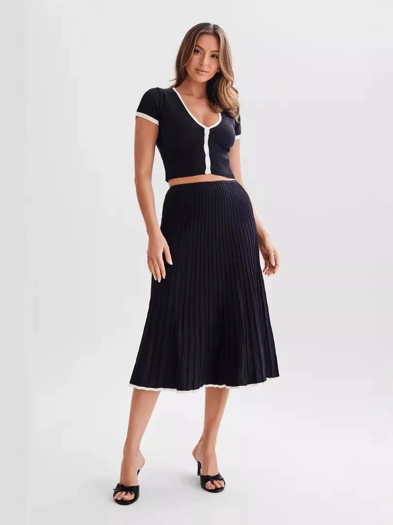 Black knit two-piece set with cropped top and pleated midi skirt, contrast trim