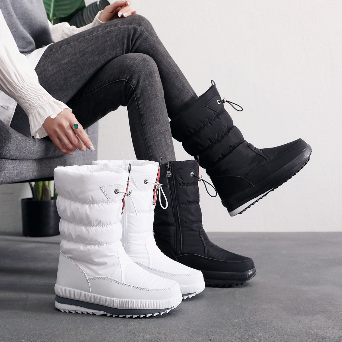 Pair of quilted snow boots in black and white, lace-up ankle and tread sole.