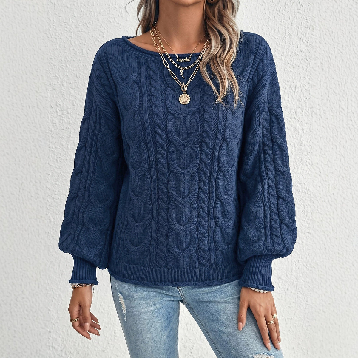 Navy cable-knit sweater with a wide neckline and voluminous sleeves