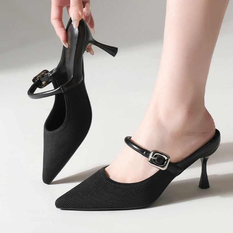 Black pointed-toe mule heels on model with single strap and square buckle stiletto