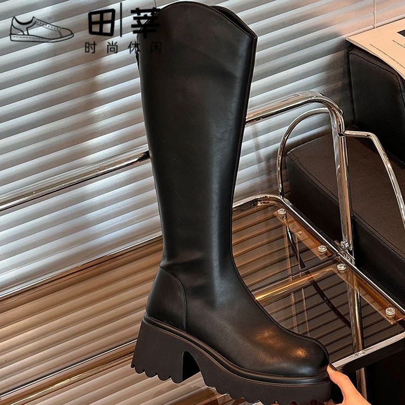 Black knee-high boots with platform lug sole, rounded toe, and chunky heel