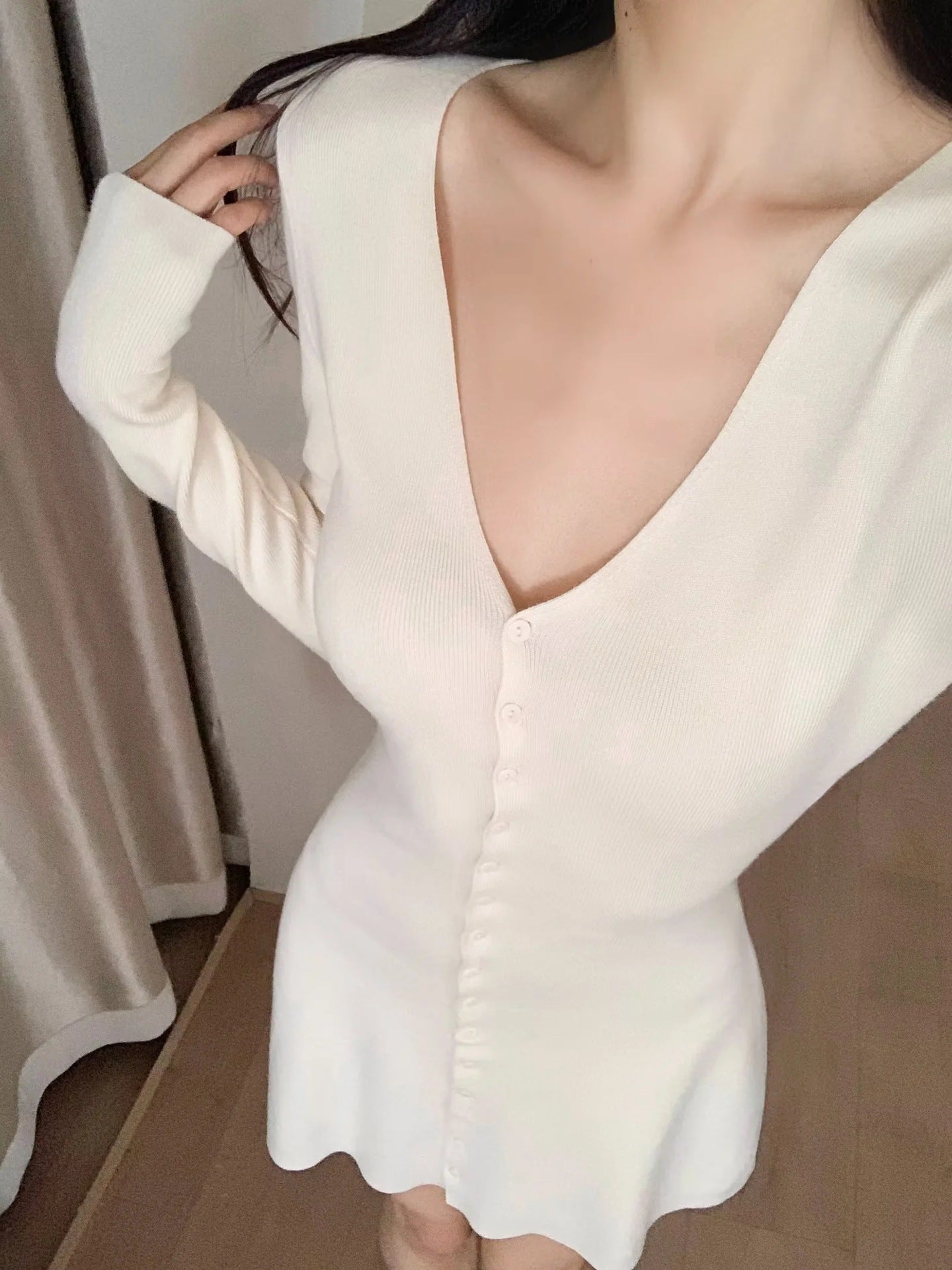 White knit mini dress with V-back, long sleeves, fitted waist, A-line hem.