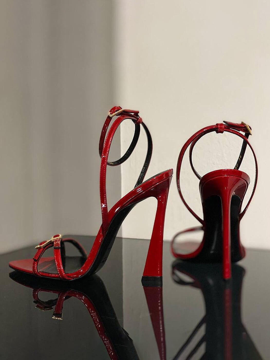 Red patent strappy stiletto heels with open toe, ankle strap and rhinestone buckle