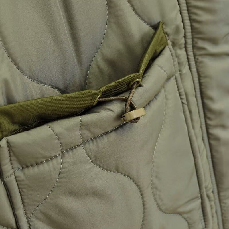 Light olive quilted jacket detail with front zipper and stitched seams