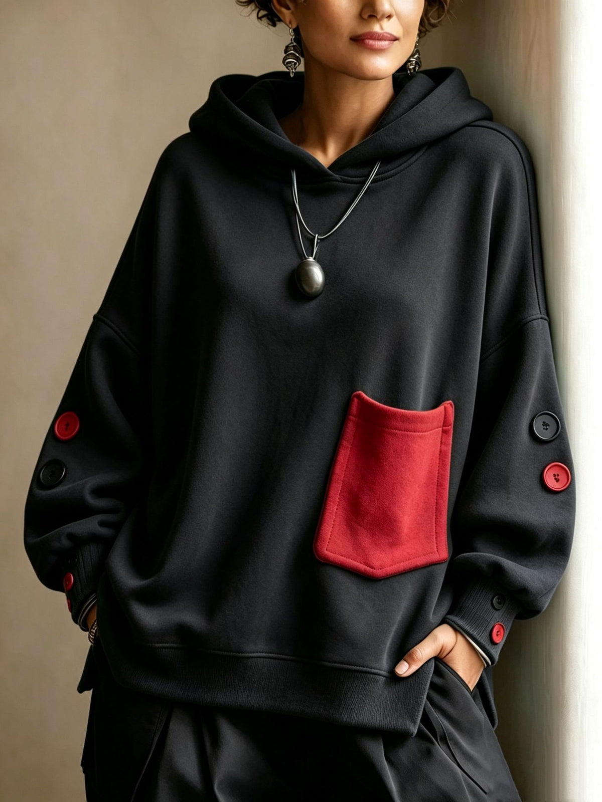 Black pullover hoodie with front kangaroo pocket, hood drawstrings, buttoned sleeve cuffs
