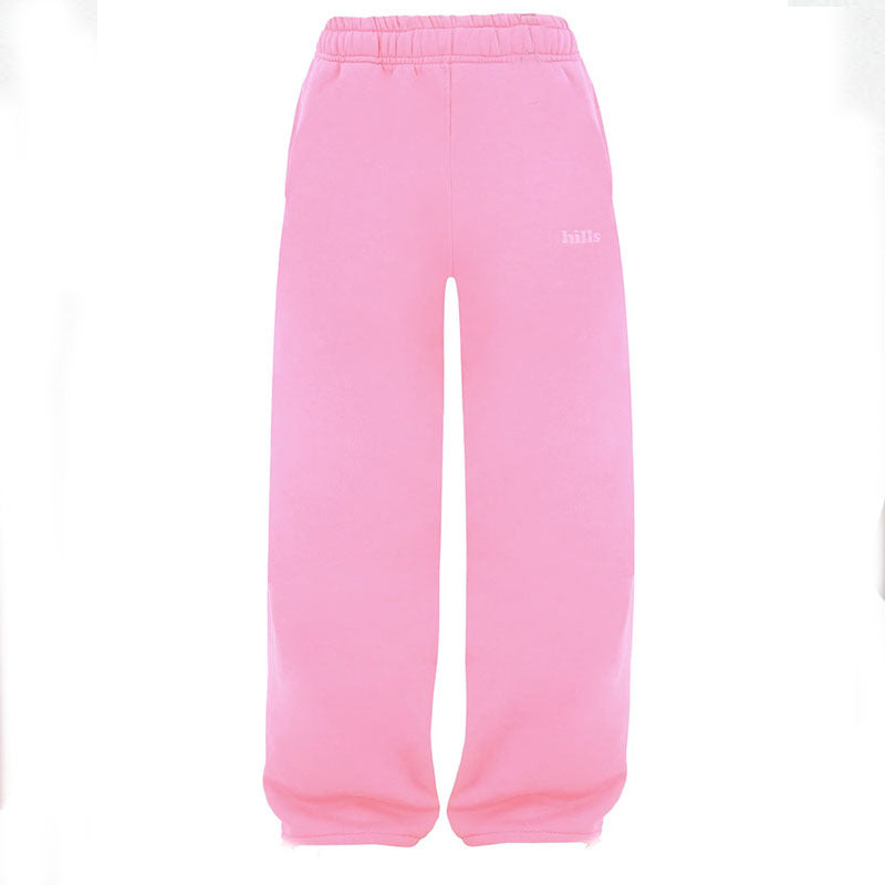 Pink sweatpants with elastic waistband, relaxed fit, and small right-leg chest text