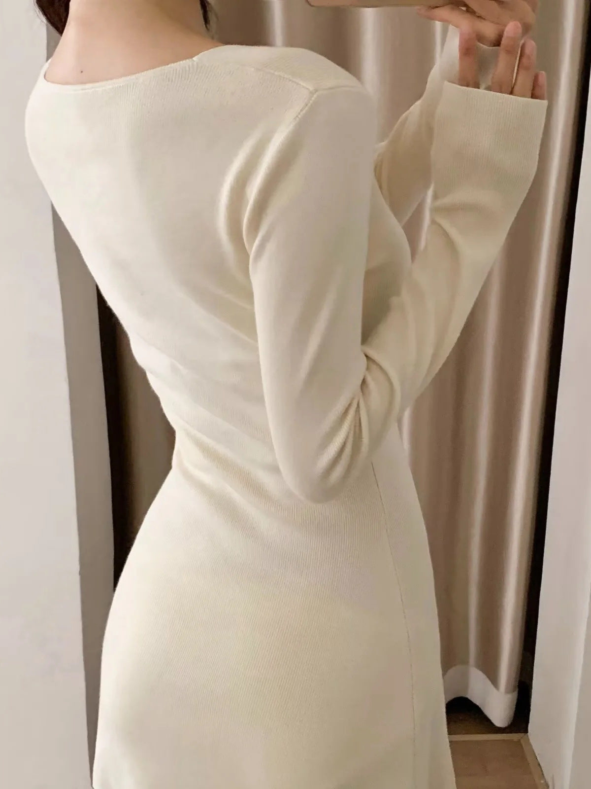 White knit mini dress back view with curved shoulders and V-back neckline, long sleeves.