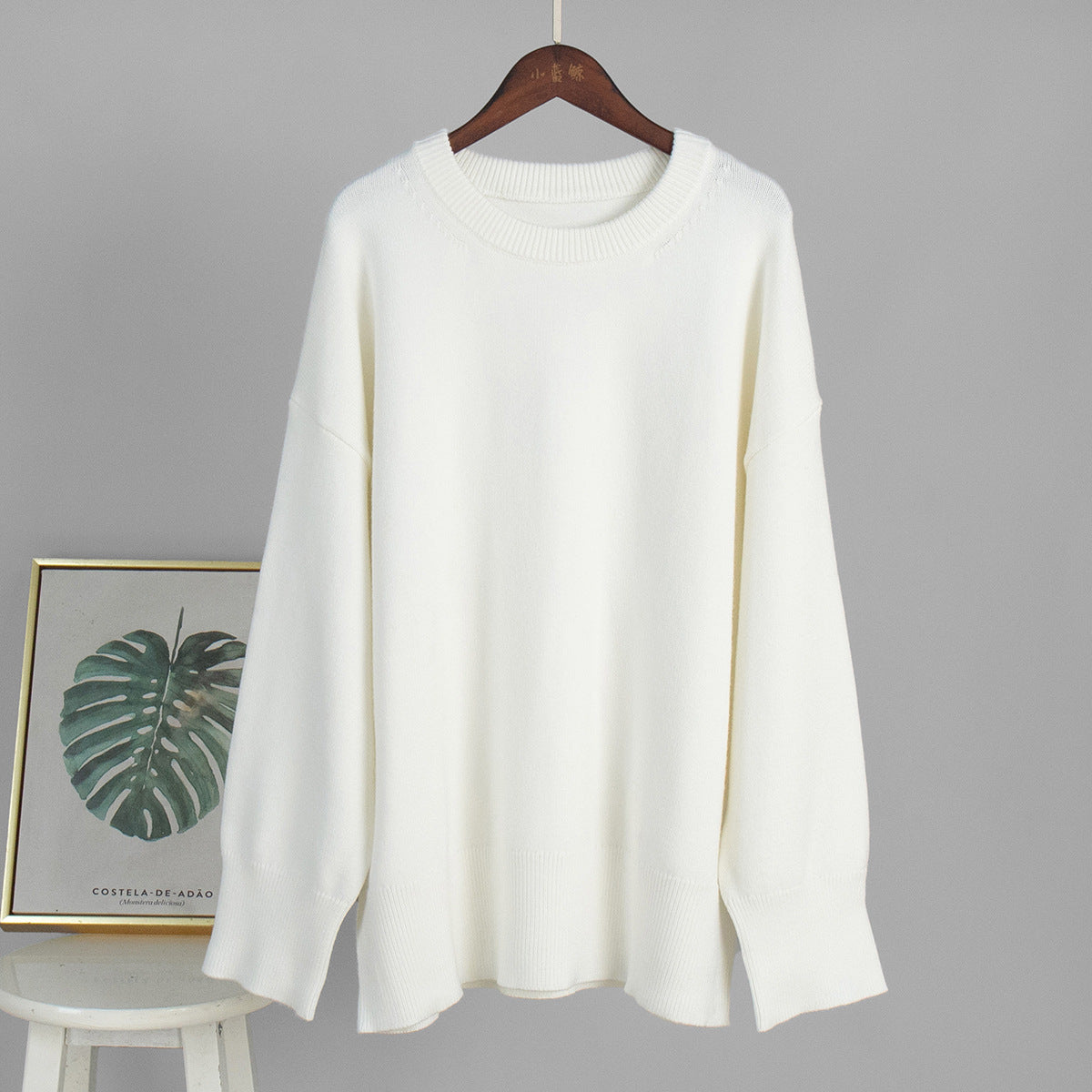 Cream white round-neck knit sweater on a hanger, long sleeves and ribbed collar