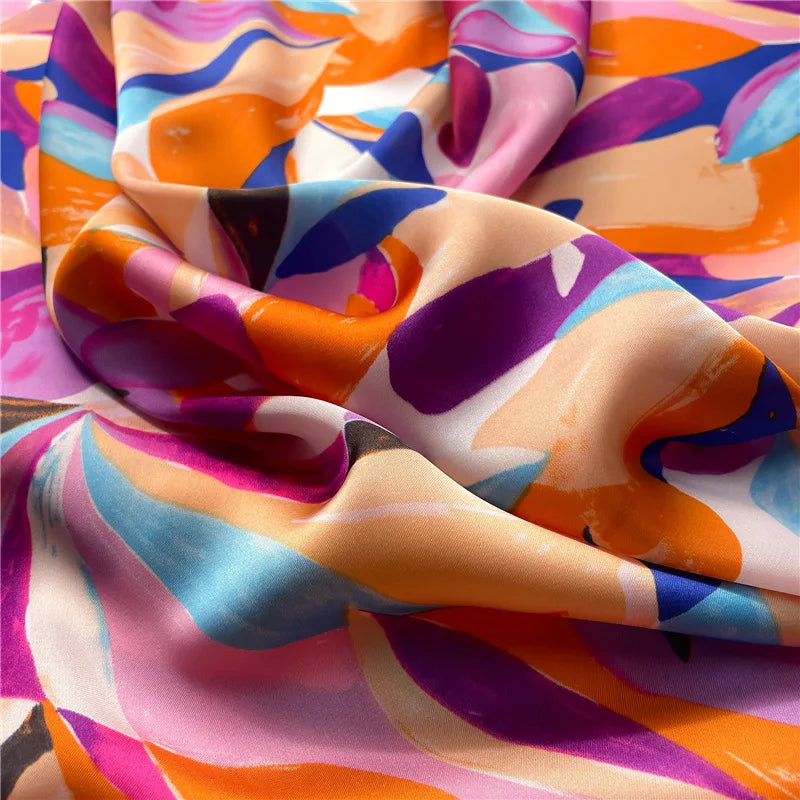 Close-up of silky scarf fabric with colorful abstract shapes and a smooth sheen