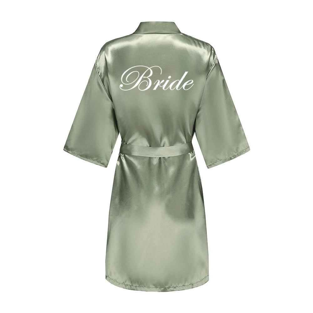 Sage green satin robe with white script “Bride” on the back, wide sleeves and tie belt