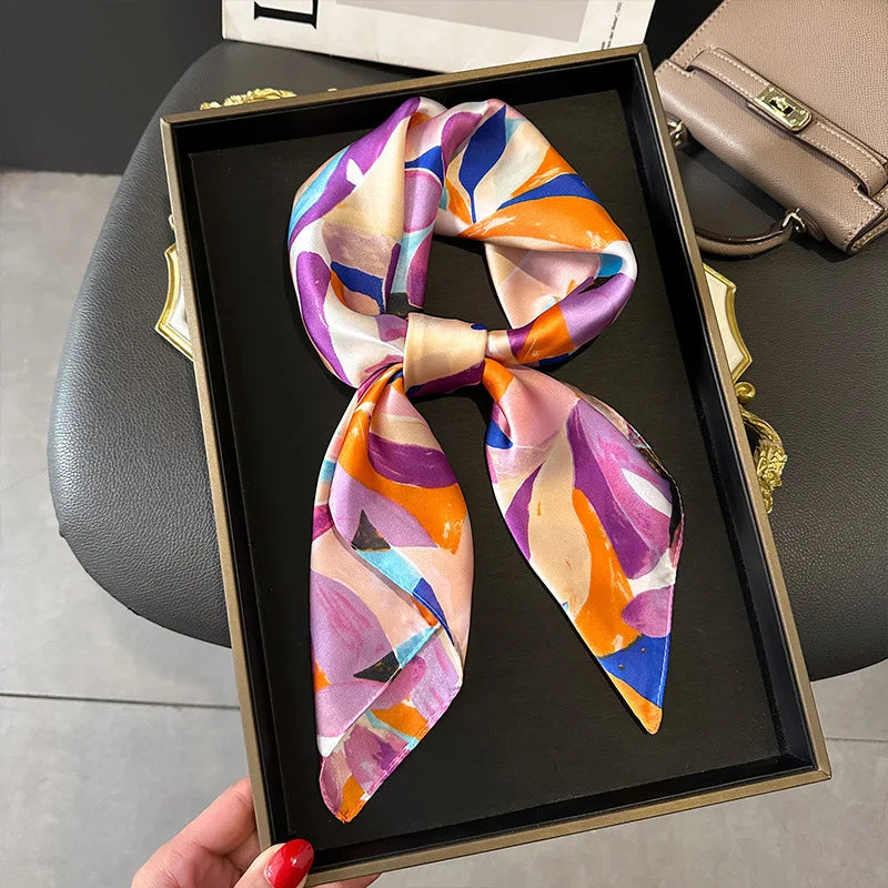 Square scarf with bright pink, orange, blue, and purple abstract print, tied at center