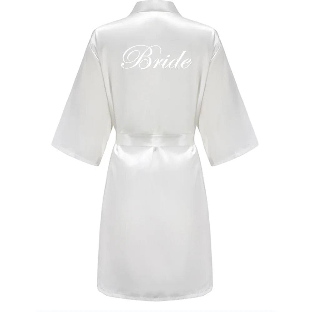White satin robe with short sleeves, waist tie, and white Bride lettering on the back
