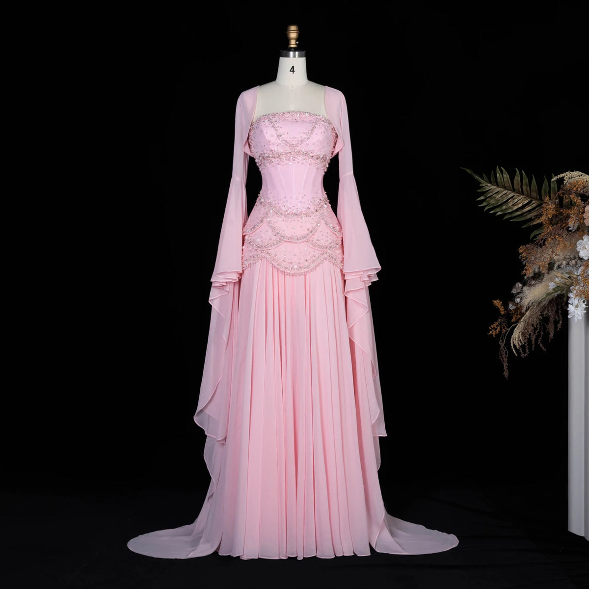 Pink beaded corset evening gown with a flowing skirt and long flared sleeves
