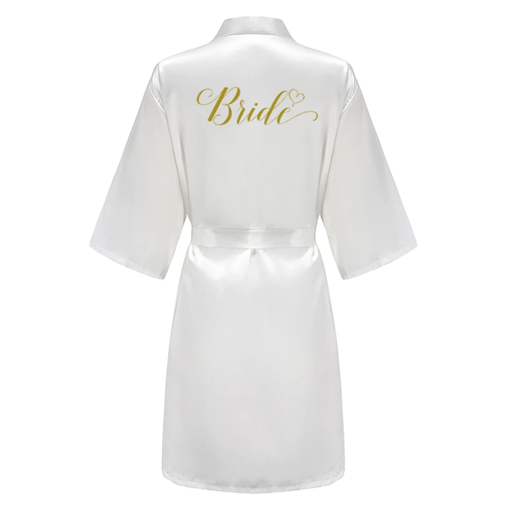 White satin robe with gold script “Bride” on the back, wide sleeves and tie belt