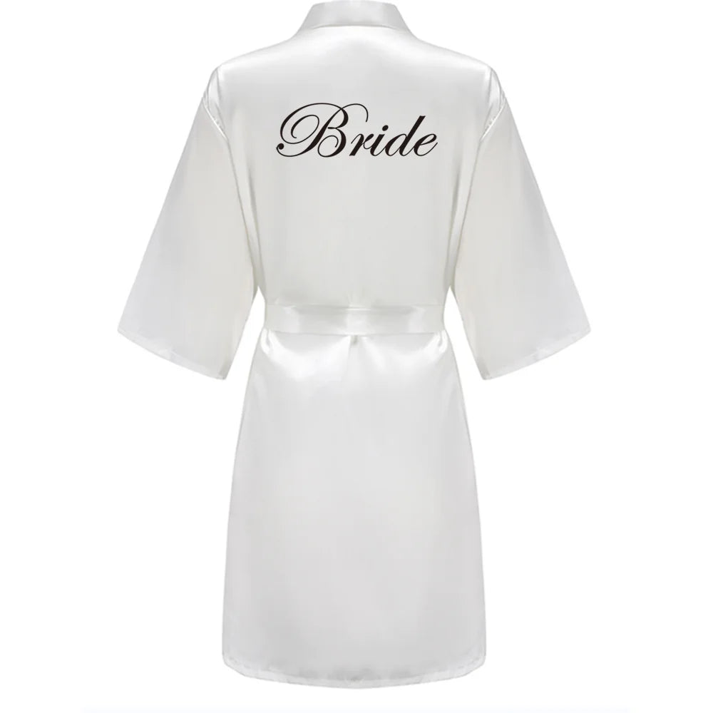 White satin robe with black script “Bride” on the back, wide sleeves and tie belt