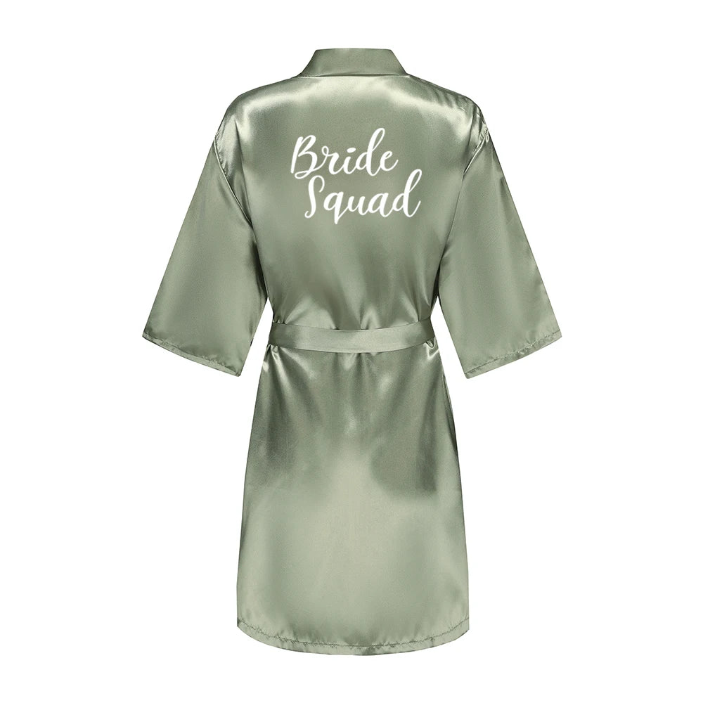 Sage green satin robe with white Bride Squad lettering on the back