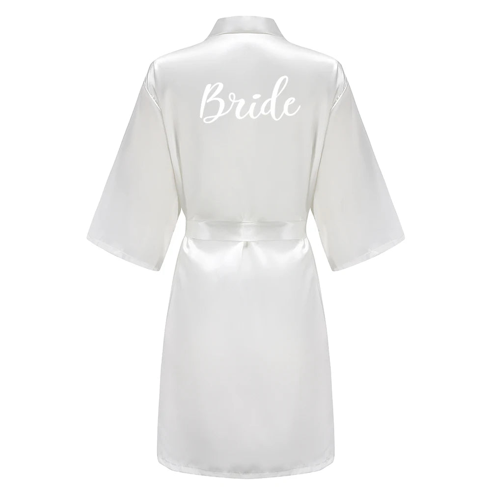 White satin robe with white script “Bride” on the back, wide sleeves and tie belt