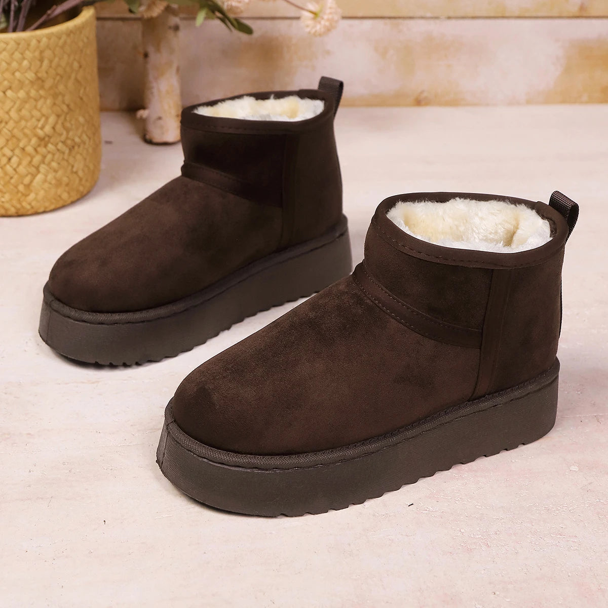 Pair of dark brown suede ankle boots with cream fleece lining, shown from the side