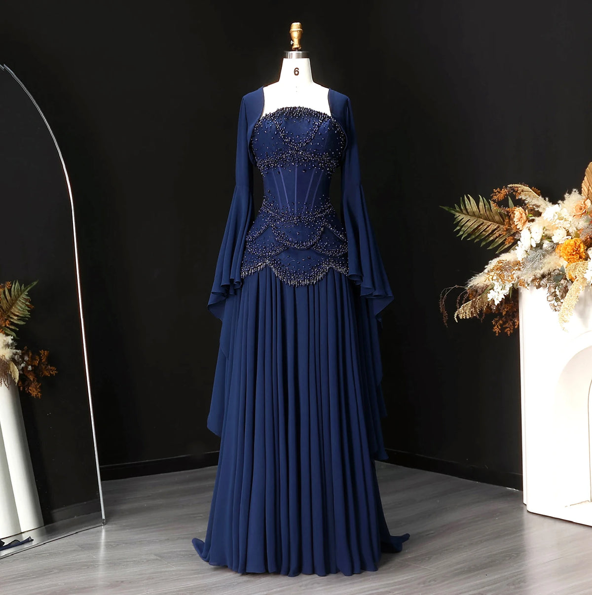 Navy blue beaded corset evening gown with a flowing skirt and long flared sleeves