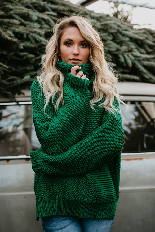 Green chunky knit high-neck sweater with long sleeves and ribbed collar.