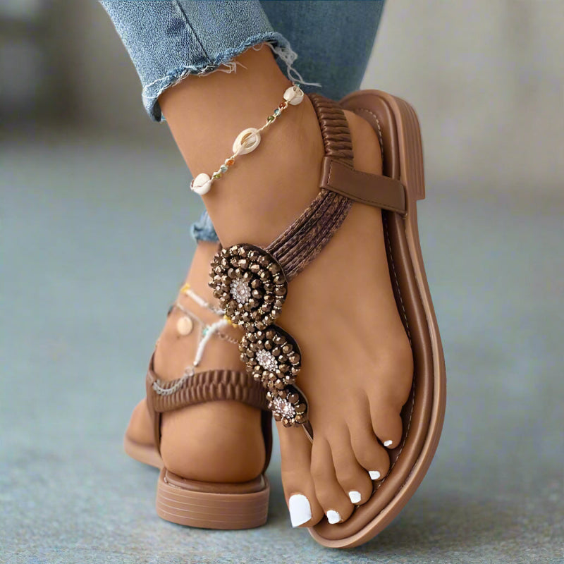 Brown flat thong sandals with woven ankle strap and beaded floral medallion detail