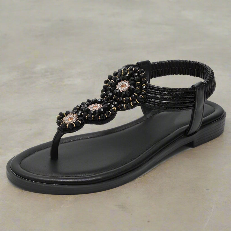 Black flat thong sandals with beaded floral ornament on thong strap