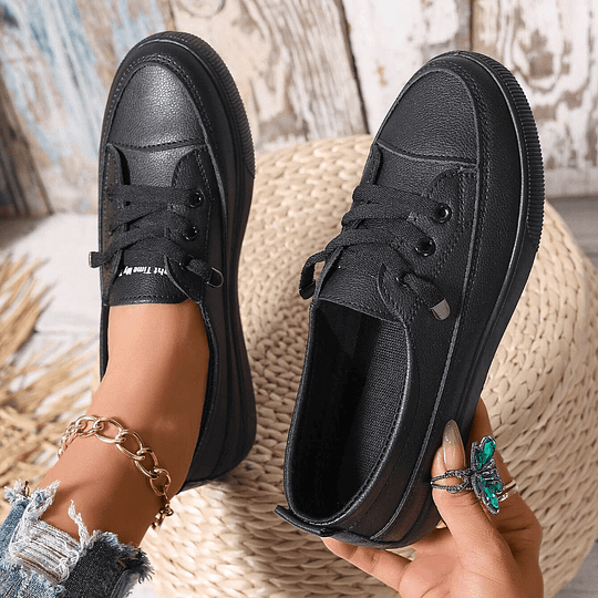 Women’s black chunky platform lace-up sneakers in faux leather, side view on feet.