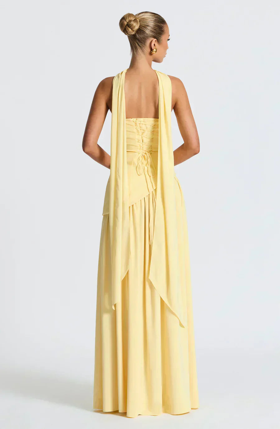 Yellow backless maxi dress with halter straps, draped waist detail, and tiered skirt