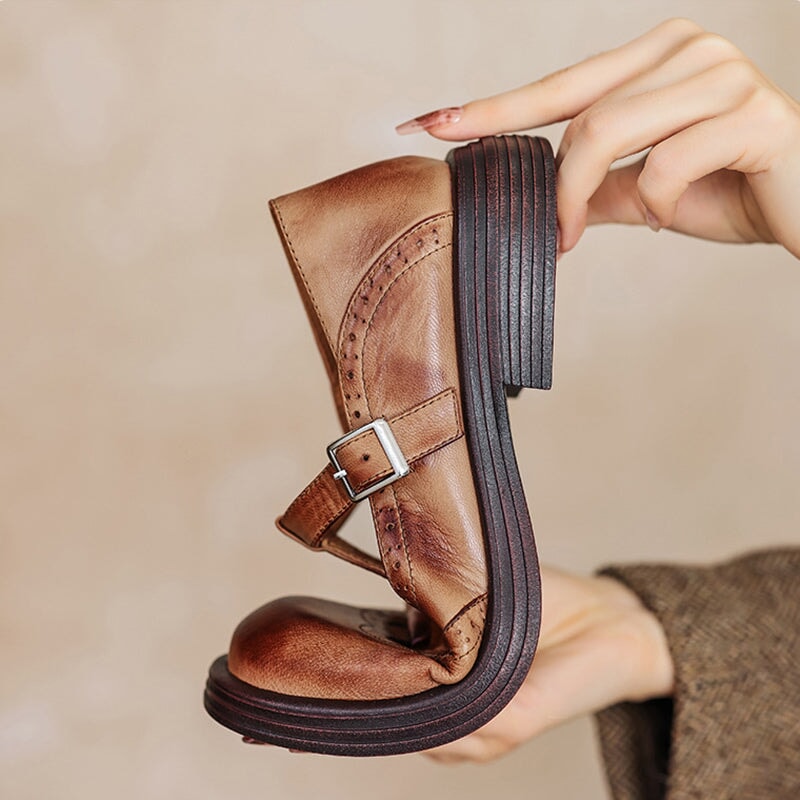 Brown leather Mary Jane flat with side T-strap buckle and cutout brogue pattern.
